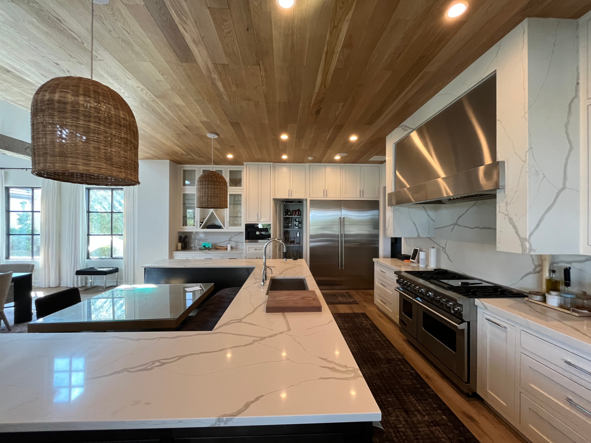 Custom kitchen with white oak plank ceiling, marble waterfall island and inset cabinetry